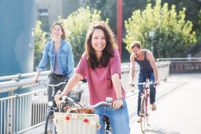 Bild vergrößern: Eine Dreiergruppe Erwachsener per Fahrrad unterwegs in der Stadt.